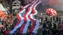Para siswa dari berbagai sekolah membentangkan bendera Merah Putih panjang saat berbaris di jalan-jalan selama acara upacara untuk memperingati HUT ke-80 Kemerdekaan Indonesia di Surabaya, Jawa Timur pada 17 Agustus 2025. (Juni KRISWANTO/AFP)