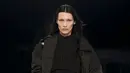 Ini potret Bella Hadid memamerkan koleksi Givenchy 2022. Dia terlihat chic memadukan hoodie dengan long coat dan baggy pants warna cokelat. (Dok/GIVENCHY).