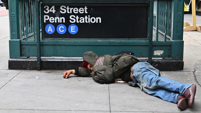 Seorang pria tidur di dekat Penn Station di Madison Square Gardens, New York City pada Kamis (17/9/2020). Sejak pandemi virus corona, para tunawisma kini  lebih terlihat seiring banyaknya penutupan banyak tempat penampungan karena alasan kesehatan. (Angela Weiss / AFP)