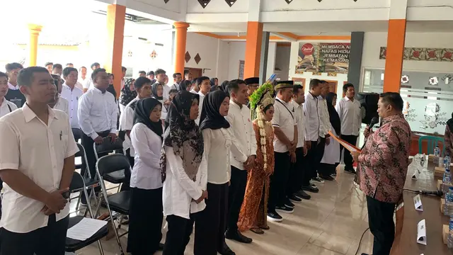 Lis Watiningsih (Tengah) mengikuti pelantikan anggota KPPS di Balai Desa Kluncing Banyuwangi yang bersamaan dengan hari resepsi pernikahanya (Istimewa)