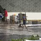 Anak-anak yang bekerja sebagai ojek payung menyeberang jalan saat hujan deras di kawasan Thamrin, Jakarta, Rabu (23/11/2022). Sejak Oktober, DKI Jakarta mulai memasuki musim penghujan yang sudah masuk ke dalam tahap ekstrem. (Liputan6.com/Faizal Fanani)