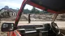 Kerusakan mencakup rumah penduduk, jalan, irigasi, persawahan, sekolah, jaringan air bersih, serta fasilitas umum lainnya. Tampak dalam foto, seorang perempuan terlihat di antara reruntuhan mobil saat berjalan di permukiman yang terdampak banjir bandang di Batang Toru, Sumatera Utara, Senin 1 Desember 2025. (AP Photo/Binsar Bakkara)