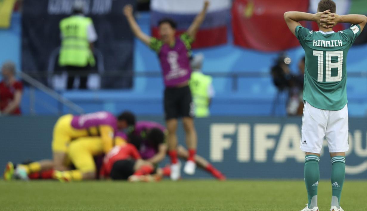 Joshua Kimmich terpaku melihat para pemain Korea Selatan merayakan gol Son Heung-min pada laga grup F Piala Dunia 2018 di Kazan Arena, Kazan, Rusia, (27/6/2018). Kekalahan tersebut membuat Jerman gagal melju ke babak 16 besar. (AP/Thanassis Stavrakis)