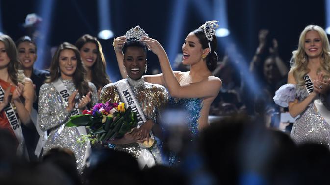 Miss Universe 2018 Catriona Grey menyematkan mahkota kepada Miss Afrika Selatan, Zozibini Tunzi, seusai dinobatkan menjadi Miss Universe 2019 pada malam final di Tyler Perry Studios, Atlanta, Minggu (8/12/2019). Zozibini Tunzi, 26, dinobatkan menjadi Miss Universe 2019. (VALERIE MACON / AFP)