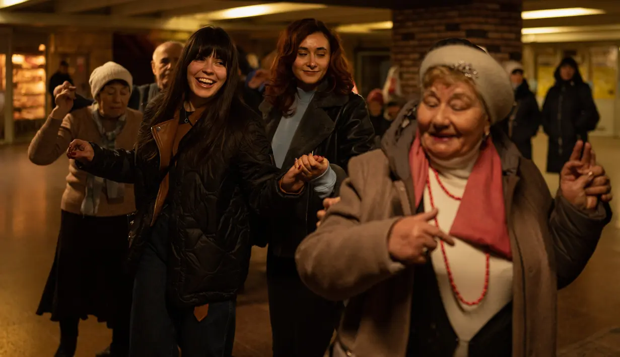 Wanita muda bergabung dengan pasangan lansia menari di Stasiun Kereta Bawah Tanah Teatralna, Kiev, Ukraina, 5 Maret 2023. Puluhan pensiunan menari selama lebih dari dua jam dalam acara akhir pekan yang telah berlangsung selama puluhan tahun dan hanya sempat terganggu oleh invasi Rusia ke Ukraina. (AP Photo/Vadim Ghirda)