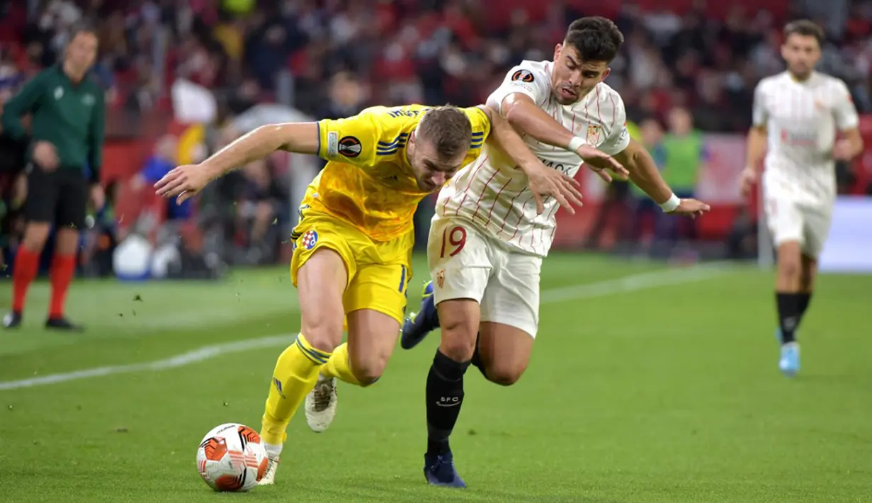 Pemain Dinamo Zagreb Makedonia Stefan Ristovski (kiri) bersaing dengan pemain Sevilla Marcos Acuna pada pertandingan sepak bola Liga Europa di Stadion Ramon Sanchez Pizjuan, Seville, Spanyol, 17 Februari 2022. Sevilla menang 3-1. (CRISTINA QUICLER/AFP)