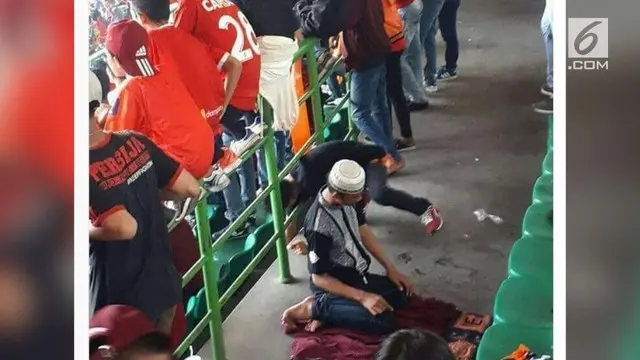 Sebuah foto menjadi viral saat pertandingan sepak bola berlangsung. Seorang supporter Jakmania terlihat sedang salat dengan khusyuk.