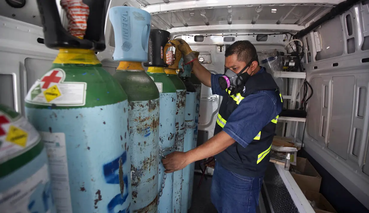 Petugas kesehatan Jose Antonio Pena mengisi ulang tangki oksigen untuk pasien COVID-19 di Distrik Iztapalapa, Mexico City, Meksiko, Selasa (26/1/2021). Mexico City menawarkan isi ulang oksigen gratis untuk pasien COVID-19. (AP Photo/Marco Ugarte)
