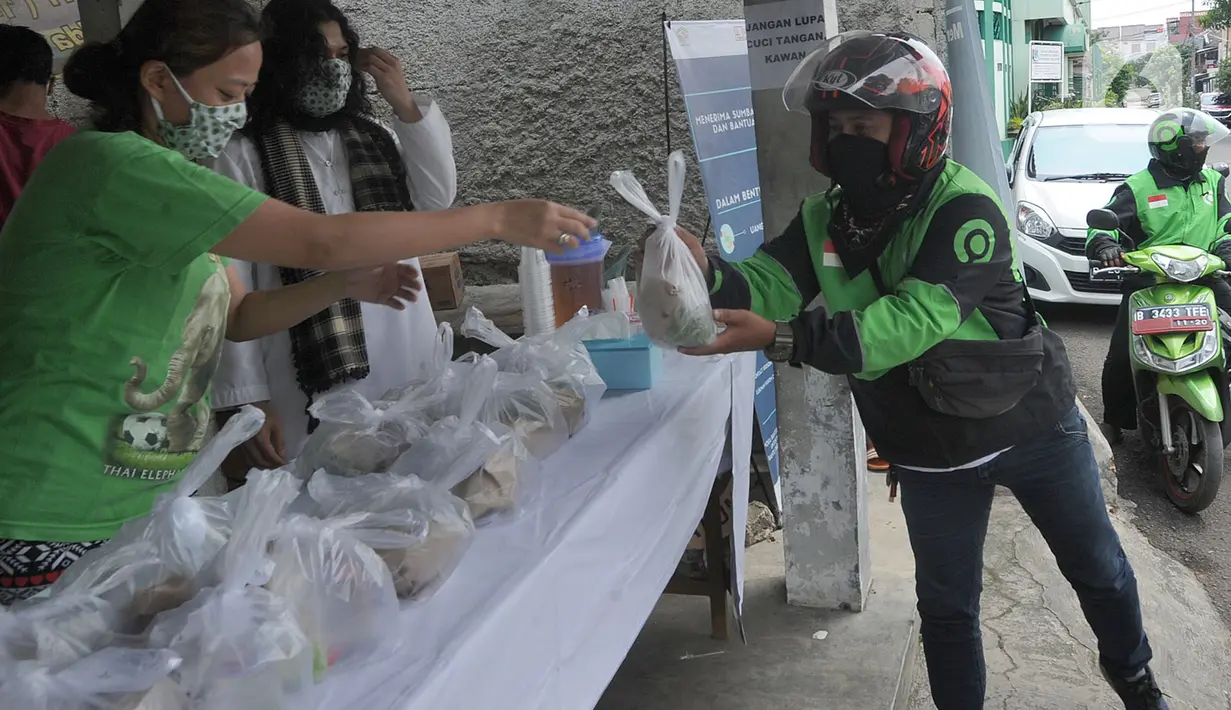Pengemudi ojek online menerima nasi bungkus gratis di Kompleks Sinar Pamulang Permai, Pamulang Barat, Tangsel, Senin (13/4/2020). Nasi bungkus gratis ini bentuk kepedulian terhadap mereka yang berpenghasilan rendah dan terdampak perekonomiannya karena penyebaran Covid-19. (merdeka.com/Arie Basuki)