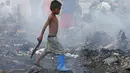 Seorang anak melintas di kawasan permukiman yang habis terbakar di Navotas, Metro Manila Filipina, Selasa (10/1). Mereka mencari barang yang masih bisa terpakai. (AP Photo/ Bullit Marquez)