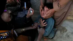 Seorang anak dipegangi orang tuanya saat petugas memberikan imunisasi polio di sepanjang jalan di Quetta, Pakistan, Senin (2/1). (REUTERS/Naseer Ahmed)