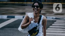 Seorang remaja mengenakan kaca mata berjalan melintasi zebra cross di Taman Sudirman, Jakarta, Rabu (6/7/2022). Tempat ini viral karena jadi ajang adu fashion anak Citayam, Bekasi hingga Bojong Gede. Mereka mengenakan kemeja flanel oversize, celana model 90-an seperti boot cut atau cutbray, sneakers klasik, dan tentu saja topi. (Liputan6.com/Faizal Fanani)