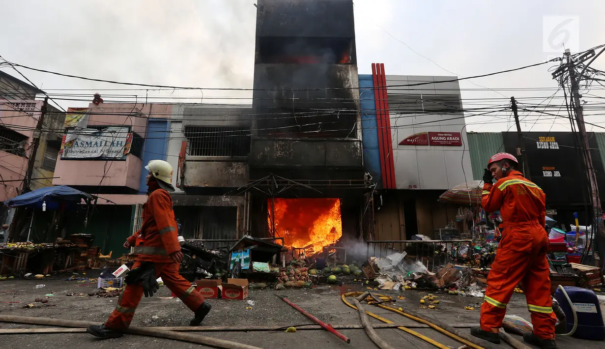 Petugas pemadam kebakaran melintas di depan ruko yang terbakar di Pasar Kebayoran Lama, Jakarta, Selasa (13/6). Kebakaran yang melanda ruko tersebut belum diketahui penyebabnya. (Liputan6.com/Johan Tallo)