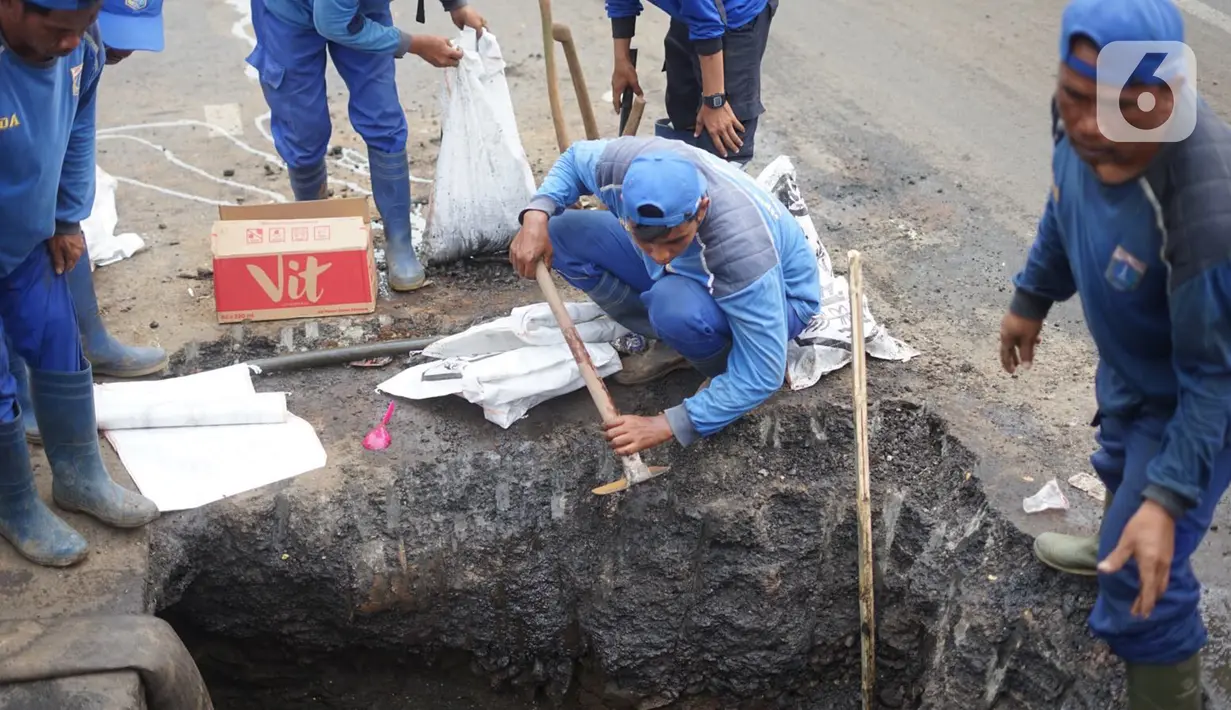 Petugas Sudin Sumber Daya Air Jakarta Timur membersihkan saluran gorong-gorong yang tertutup lumpur dan sampah di kawasan Pasar Rebo, Kamis (19/3/2020). Pembersihan untuk memperlancar sistem drainase yang tersumbat dan kerap menimbulkan genangan air di kawasan itu. (Liputan6.com/Immanuel Antonius)