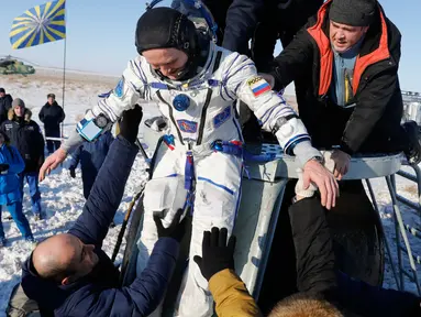 Tim penyelamat antariksa Rusia membantu kosmonot Rusia Sergey Ryazanskiy sesaat setelah pendaratan kapsul Soyuz MS-05 di Kazakhstan (14/12). (AP/ Dmitri Lovetsky/Pool)
