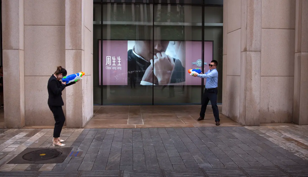 Pekerja kantor pria dan wanita bermain senjata air di luar kantor, Beijing, (13/7). Karyawan di China terkadang menghabiskan waktu berjam-jam di tempat kerja dan beralih bermain dengan ide kreatif untuk menghilangkan stres. (AP Photo/Mark Schiefelbein)