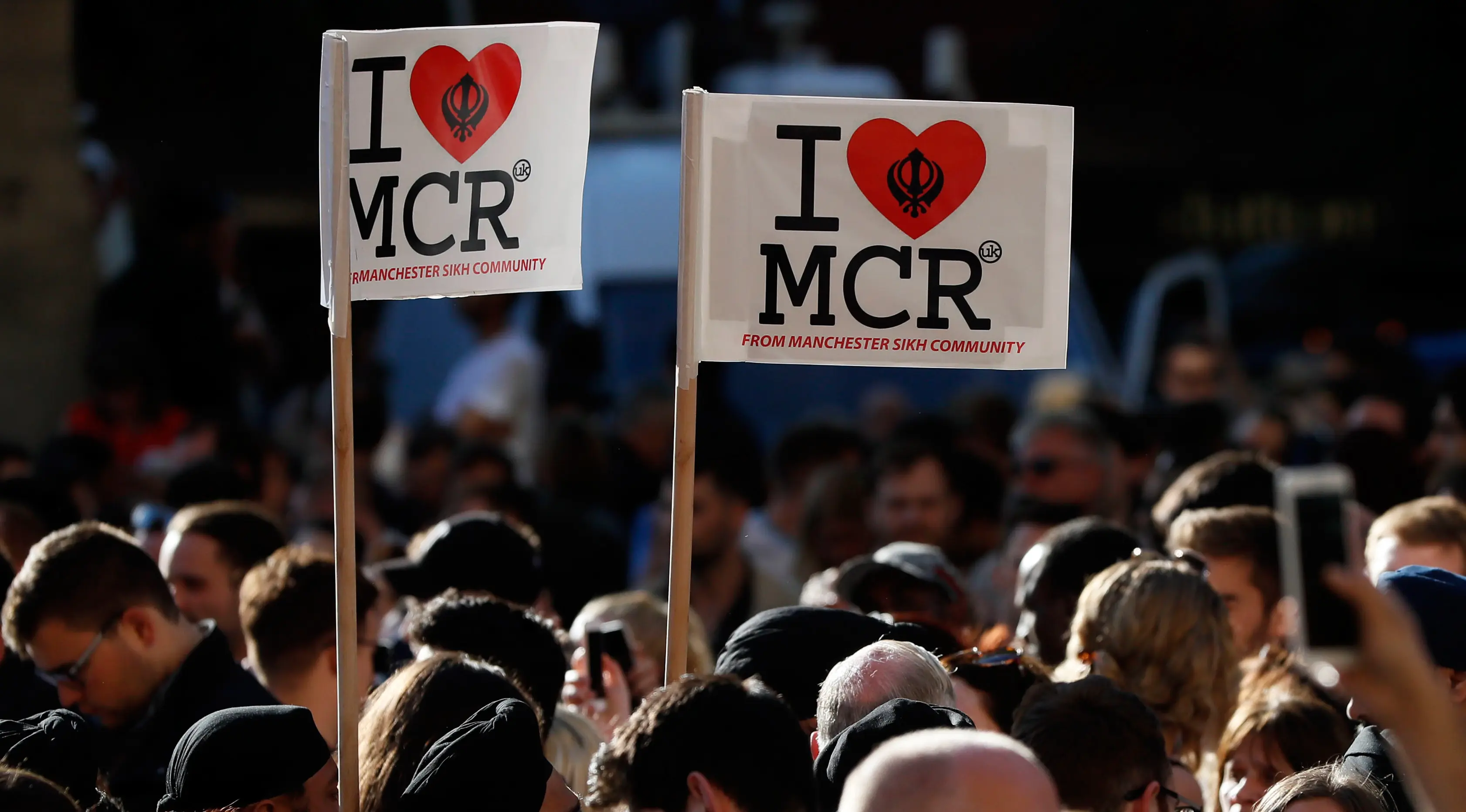 Sejumlah orang membawa poster 'I Love MCR' di pusat kota Manchester, sehari setelah ledakan bom saat konser Ariana Grande, Selasa (23/5). Mereka menggelar doa bersama untuk korban serangan bom yang menewaskan 22 orang (AP Photo/Kirsty Wigglesworth)