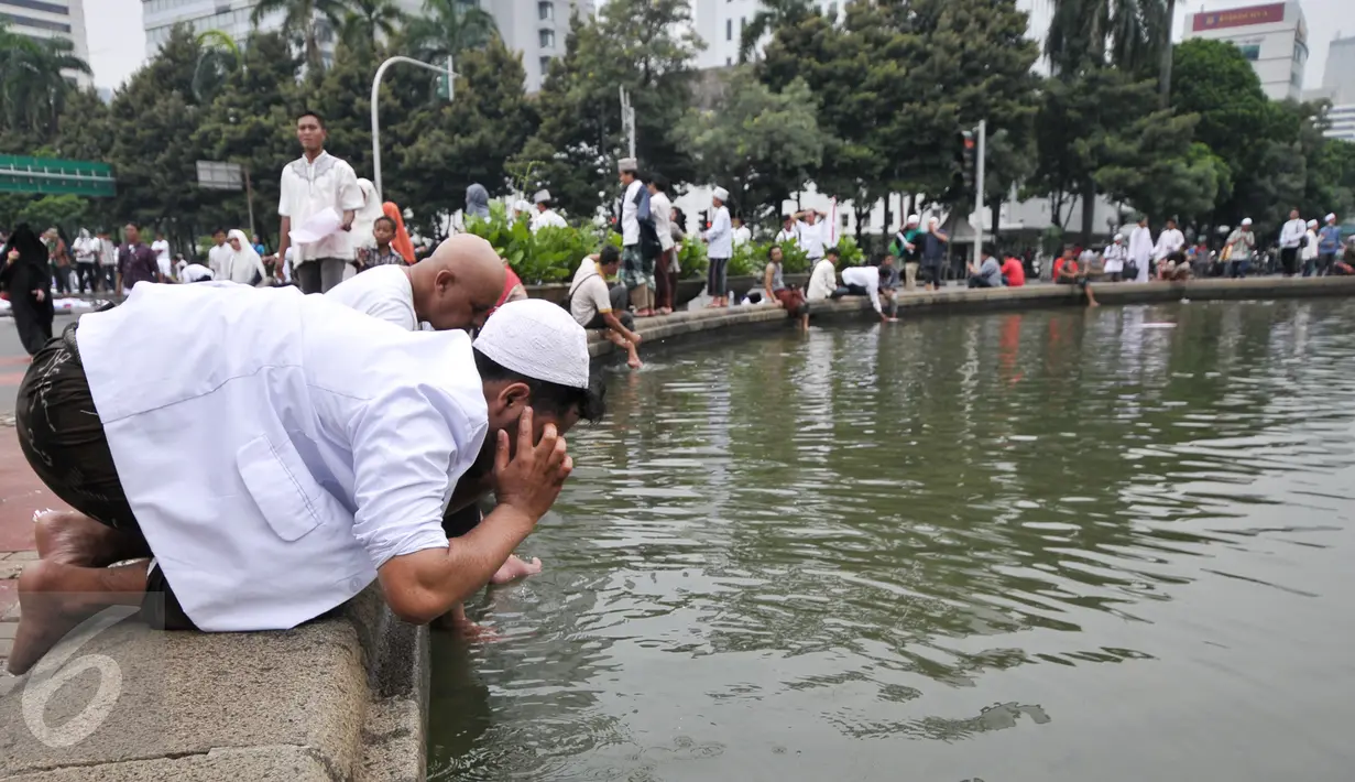 Sejumlah massa demonstran memanfaatkan air kolam Bundaran Patung Kuda untuk wudhu salat Jumat, Jakarta, Jumat (4/11). Sebagian massa demonstan gelar salat Jumat di area Bundaran Patung Kuda. (Liputan6.com/Yoppy Renato)