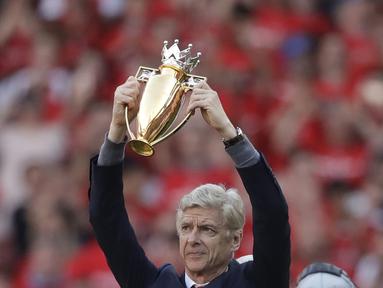 Arsene Wenger memegang trofi hadiah perpisahan di Emirates Stadium, London, (6/5/2018). Arsene Wegner mengumumkan mundur sebagai pelatih setelah 22 tahun bersama Arsenal. (AP/Matt Dunham)