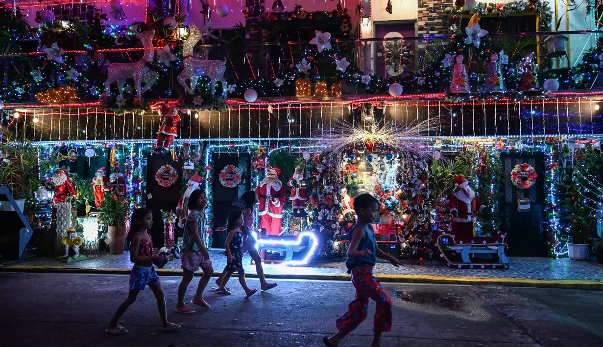 Anak-anak berjalan melewati sebuah rumah bertema Natal di Manila (21/12/2022). Perayaan Natal tinggal menghitung hari, warga Manila antusias mengunjungi rumah yang didekor dengan ornamen dan hiasan Natal itu. (AFP/Jam Sta Rosa)