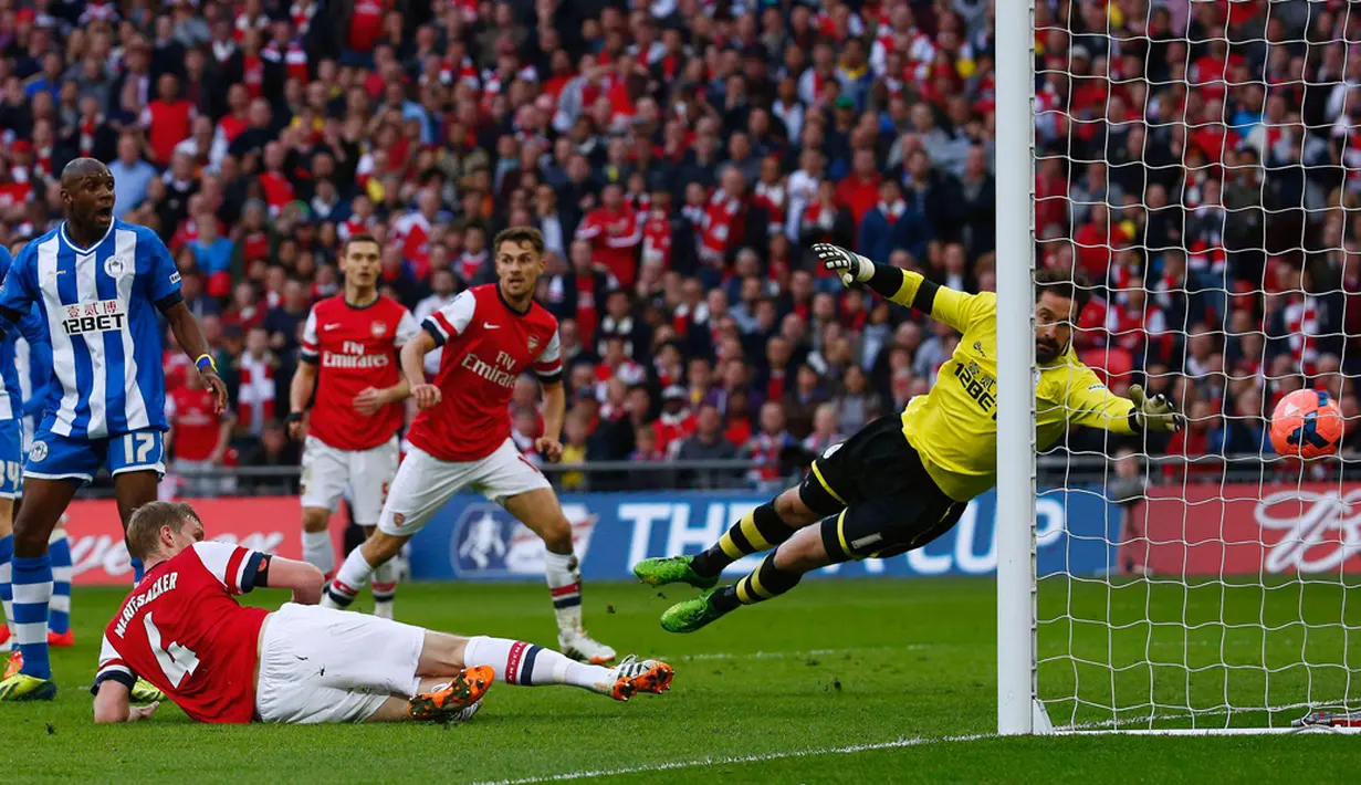 Per Mertesacker (bawah) berhasil mencetak gol ke gawang Wigan Athletic saat berlaga dalam semifinal Piala FA Inggris di Stadion Wembley, (12/4/2014). (REUTERS/Eddie Keogh)