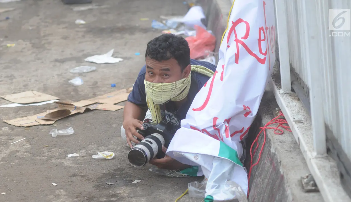 Jurnalis melindungi dirinya saat meliput demontrasi yang memanas di depan gedung Dewan Perwakilan Rakyat (DPR), Senayan, Jakarta, Selasa (24/9/2019). Polisi menembakkan gas air mata dan meriam air untuk membubarkan massa aksi yang menolak RKUHP dan RUU kontroversial lain. (merdeka.com/Arie Basuki)