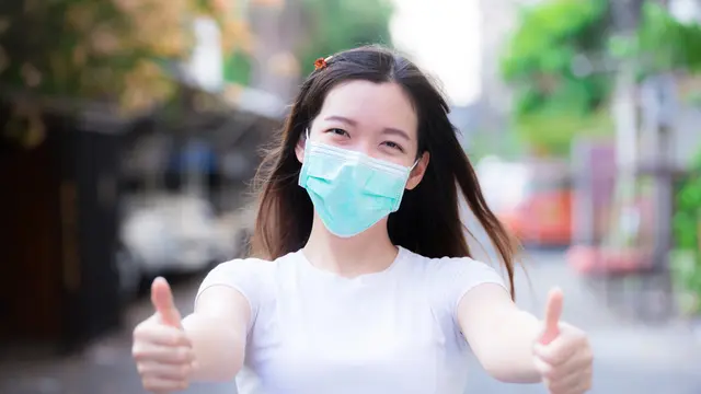Seorang wanita tersenyum di balik masker
