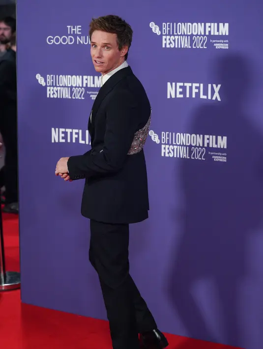 <p>Aktor Inggris Eddie Redmayne berpose untuk fotografer saat tiba untuk pemutaran perdana film 'The Good Nurse' pada acara London Film Festival di London, Inggris, 10 Oktober 2022. Aktor berusia 40 tahun itu tampak necis dalam setelan jas hitam karya Alexander McQueen yang menampilkan payet pada bagian belakang jasnya. (Photo by Scott Garfitt/Invision/AP)</p>