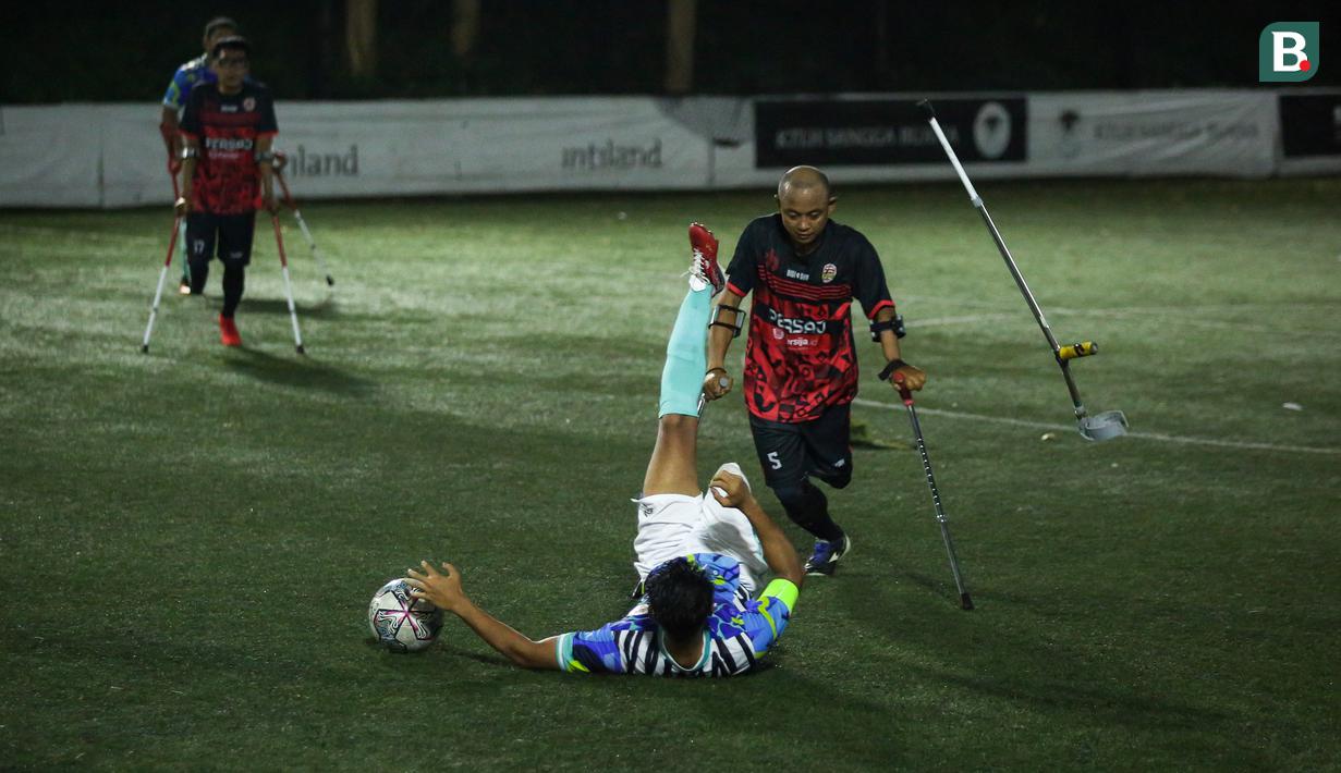 Pemain Timnas Sepak Bola Amputasi Indonesia, Aditya terajatuh usai berebut bola dengan pemain Persaj jakarta saat laga uji coba untuk persiapan Piala Dunia Amputasi 2022 di Serenia Hills Mini Soccer, Jakarta Selatan, Senin (08/08/2022). Garuda INAF menang dengan skor 13-0. (Bola.com/Bagaskara Lazuardi)