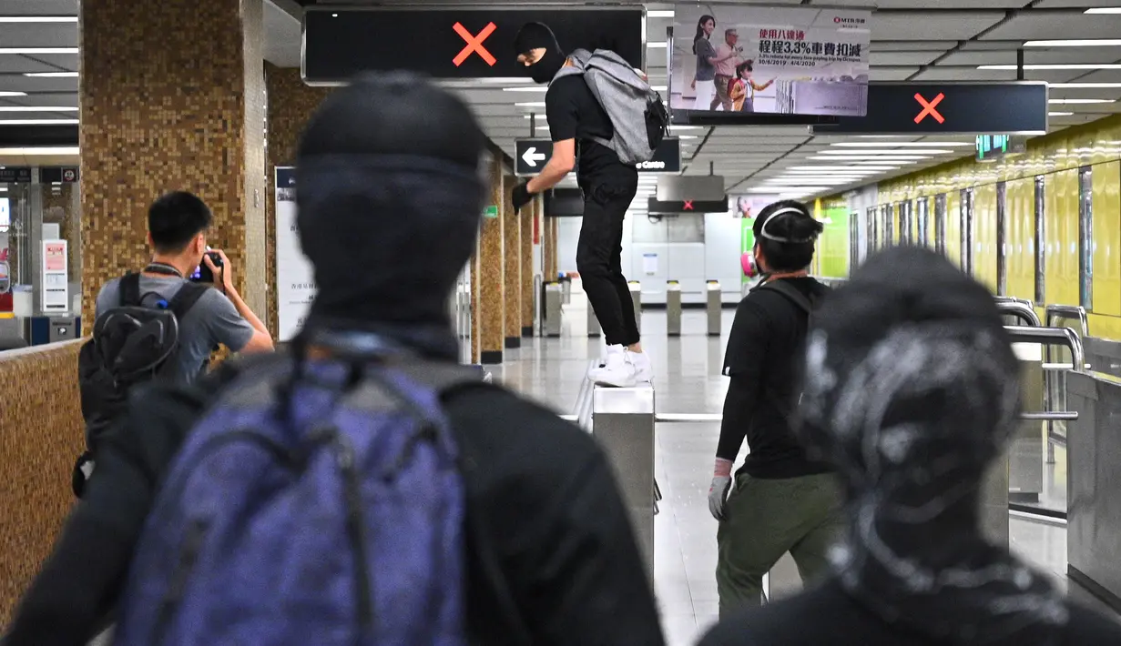 Sejumlah demonstran bertopeng merusak Stasiun MTR Wong Tai Sin di Distrik Kowloon, Hong Kong, Senin (7/10/2019). Eskalasi kerusuhan di Hong Kong semakin membesar setelah pemerintah mengeluarkan larangan demonstrasi menggunakan masker atau UU Antitopeng. (Philip FONG/AFP)