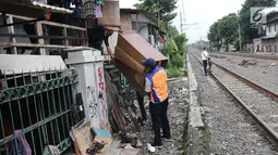 Petugas memindahkan lemari milik warga setempat saat melakukan penertiban lapak dan bangunan liar di sepanjang jalur kereta di kawasan Grogol, Jakarta Barat, Kamis (22/2). (Liputan6.com/Arya Manggala)
