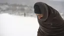 Seorang migran dengan dibungkus selimut berjalan melewati salju di kamp Lipa, barat daya Bosnia, dekat perbatasan dengan Kroasia, Sabtu (26/12/2020). Ratusan migran terdampar di tenda-tenda kumuh dan terbakar di Bosnia, di tengah hujan salju yang lebat dan suhu membeku. (AP Photo/Kemal Softic)
