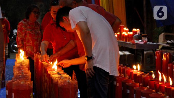 Warga keturunan Tionghoa menyalakan lilin saat melaksanakan sembahyang pada malam Tahun Baru Imlek 2571 di Vihara Dhanagun, Bogor, Jawa Barat, Jumat (24/1/2020). (merdeka.com/magang/Muhammad Fayyadh)