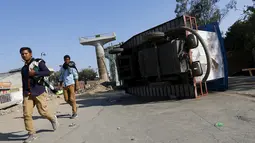 Warga berjalan di dekat kendaran yang terbalik akibat demonstrasi di negara bagian Haryana, India,Minggu (21/2). Pihak berwenang mengambil langkah mengatasi masalah pasokan air yang menimbulkan aksi kekerasan yang menewaskan 10 orang (REUTERS/Adnan Abidi)