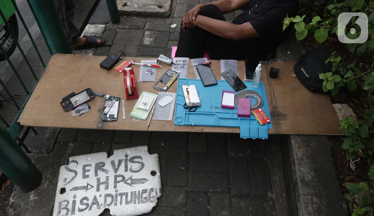 Penjual jasa perbaikan telepon genggam menawarkan jasa di trotoar jalan Mayjen Sutoyo depan Mall Pusat Grosir Cililitan (PGC), Jakarta, Rabu (14/7/2021). Imbas dari penutupan Mall PGC selama PPKM Darurat Jawa-Bali, mereka terpaksa menawarkan jasa di pinggir jalan. (Liputan6.com/Helmi Fithriansyah)