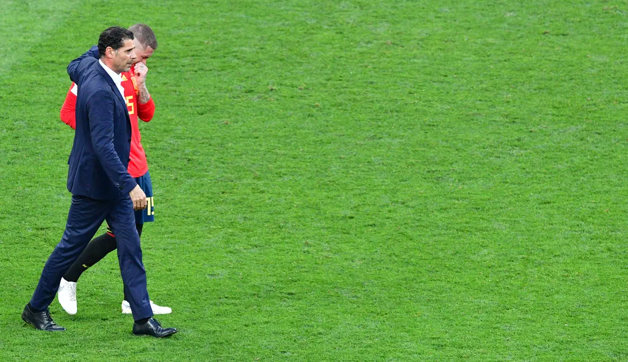 Bek Spanyol, Sergio Ramos berjalan sambil menangis bersama pelatih Fernando Hierro usai pertandingan melawan Rusia di babak 16 besar Piala Dunia 2018 di Stadion Luzhniki, Moskow, Rusia (1/7). (AFP Photo/Mladen Antonov)