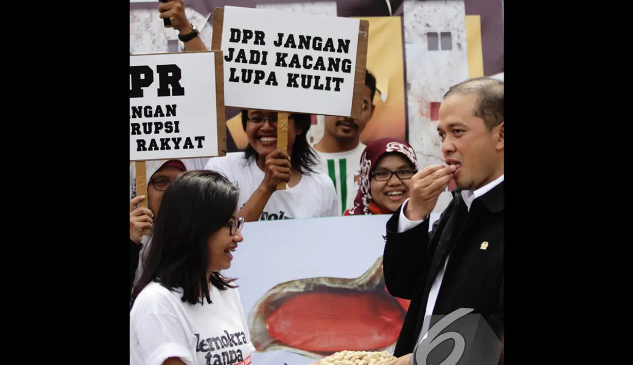  Seorang anggota DPR menerima tawaran aktivis ICW untuk memakan kacang saat memperingati Hari Anti Korupsi Sedunia, Jakarta, Selasa (9/12/2014). (Liputan6.com/Faizal Fanani)