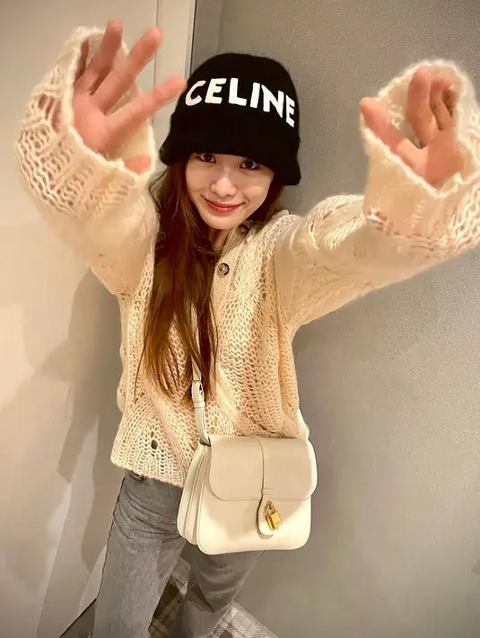 Nana tampil mengenakan oversized sweater rajut dengan celana jeans abu-abu, dan bucket hat hitam, yang disempurnakannya dengan Celine Tabou Bag berwarna putih. Foto: Document/Celine.