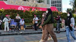 Musisi mengelar pertunjukan musik bernuansa Natal di jalur Pedestrian Bundaran HI, Jakarta Pusat, Selasa (20/12/2022). Pergelaran musik bernuansa Natal tersebut sebagai bentuk pertunjukan untuk menghibur warga yang melintas di Kawasan itu. (Liputan6.com/Angga Yuniar)