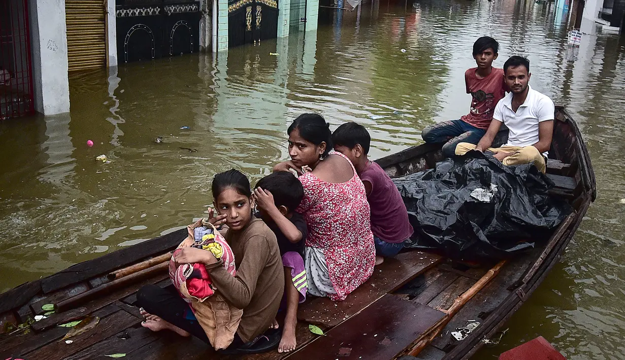 Warga menaiki perahu saat melintasi jalan yang terendam banjir di Chhota Baghara, Allahabad, India, Rabu (11/8/2021). Hujan lebat menyebabkan banjir di Allahabad. (SANJAY KANOJIA/AFP)