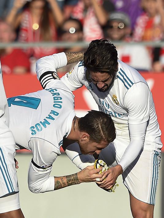 Pemain Real Madrid, Sergio Ramos (tengah) mencium sepatu rekannya Isco saat merayakan gol melawan Girona pada lanjutan La Liga Santander di Municipal de Montilivi stadium, Girona , (29/10/2017). Madrid kalah 1-2. (AFP/Josep Lago)