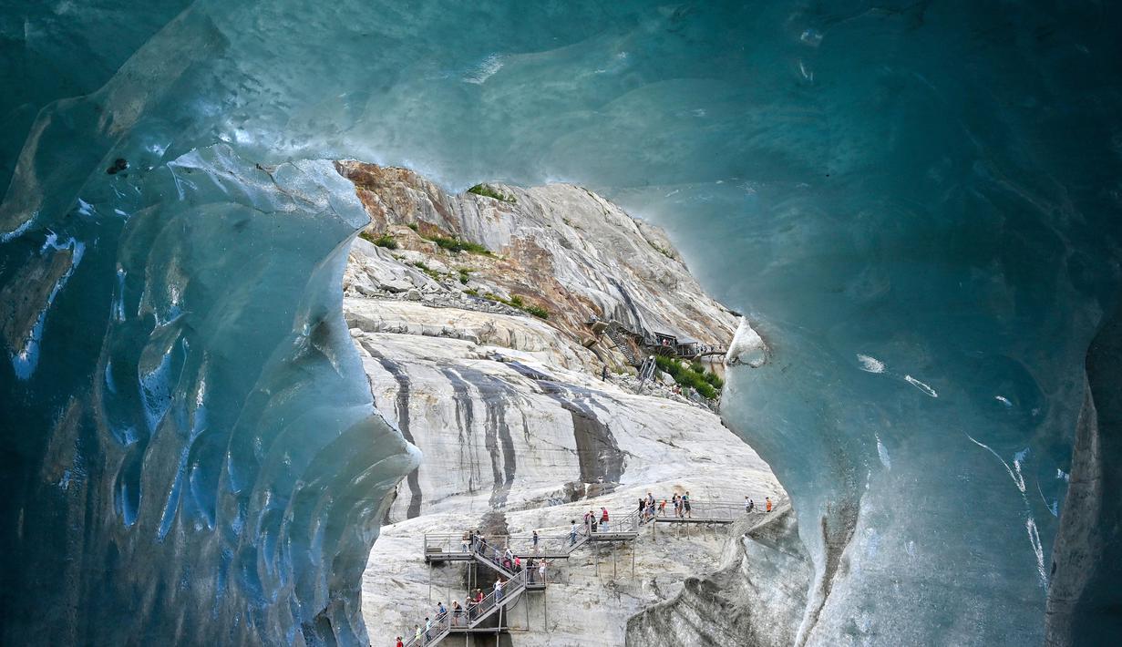 Wisatawan mendaki tangga saat mengunjungi sebuah gua es, "La Grotte de Glace", di gletser Mer de Glace (Lautan Es) di Chamonix-Mont-Blanc, Pegunungan Alpen Prancis, Jumat (19/7/2019). Gua yang berada di lereng Mont Blanc ini memiliki panjang 7 km dengan kedalaman 200 meter. (PHILIPPE DESMAZES/AFP)