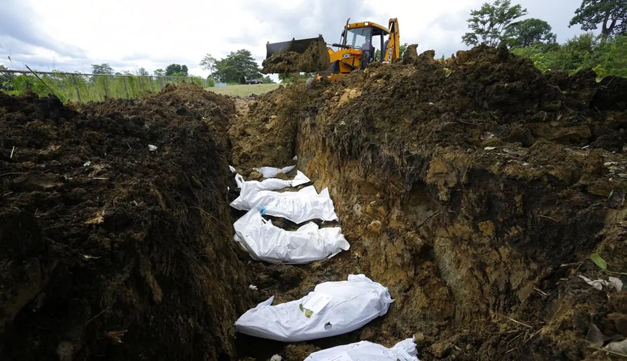 Sebuah backhoe membawa tanah untuk mengubur sekelompok imigran yang tewas saat mencoba menyeberangi Celah Darien di Pemakaman Guayabillo, Agua Fria, Panama, 30 September 2021. Celah Darien berupa lembah dan rawa-rawa di Amerika Tengah yang memutus Jalan Pan Amerika. (AP Photo/Arnulfo Franco)