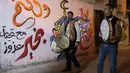 Dikenal sebagai musaharati, pekerja publik secara tradisional berjalan melalui lingkungan Muslim sejak pukul 2 pagi untuk membangunkan mereka yang berpuasa selama bulan suci Ramadhan. (Photo by SAID KHATIB / AFP)