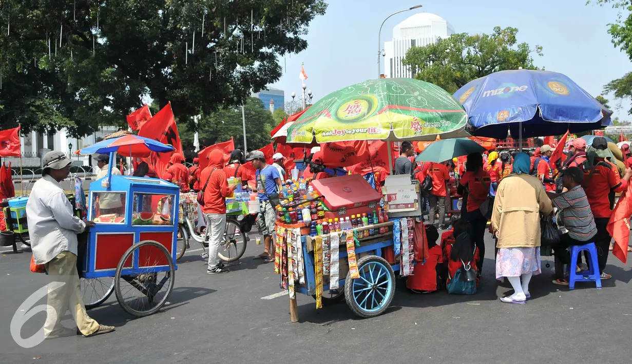 Pedagang berkumpul saat demo memperingati hari lahirnya organisasi buruh internasional World Federation of Trade Unions (WFTU) di Jakarta (3/10/2015).  Sejumlah PKL memanfaatkan demo buruh untuk meraup sedikit keuntungan. (Liputan6.com/Gempur M Surya)