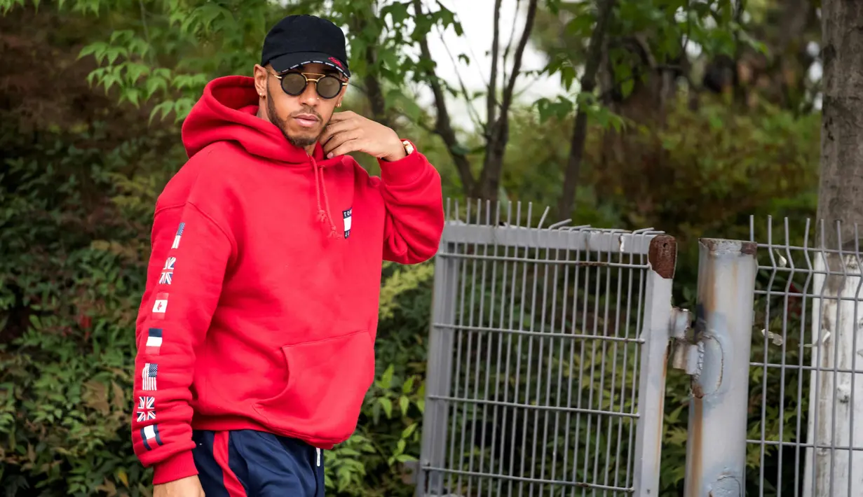 Pembalap Mercedes asal Inggris Lewis Hamilton berjalan di paddock sebelum Grand Prix Formula Satu China di Shanghai (12/4). Hamilton keren mengenakan kaca mata dan jaket berwarna merah. (AFP Photo/Johannes Eisele)