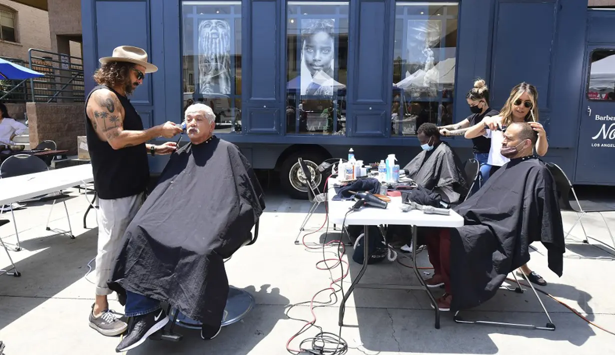 Penata rambut selebriti Jason Schneidman (kiri) dari The Men's Groomer mencukur rambut Samuel Velasquez saat cukur rambut gratis untuk para tunawisma dalam Los Angeles Mission di Los Angeles, California, Amerika Serikat, 12 Juli 2021. (Frederic J. BROWN/AFP)