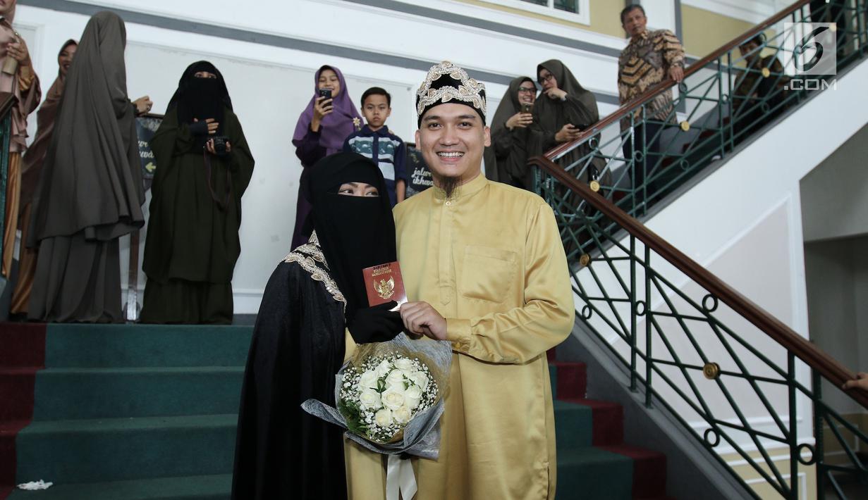 Pesinetron Egi John bersama pasangannya Kamilia Yasmin menunjukan buku nikah usai akad nikah di kawasan Cinere, Jakarta, Sabtu (1/7). (Liputan6.com/Herman Zakharia)