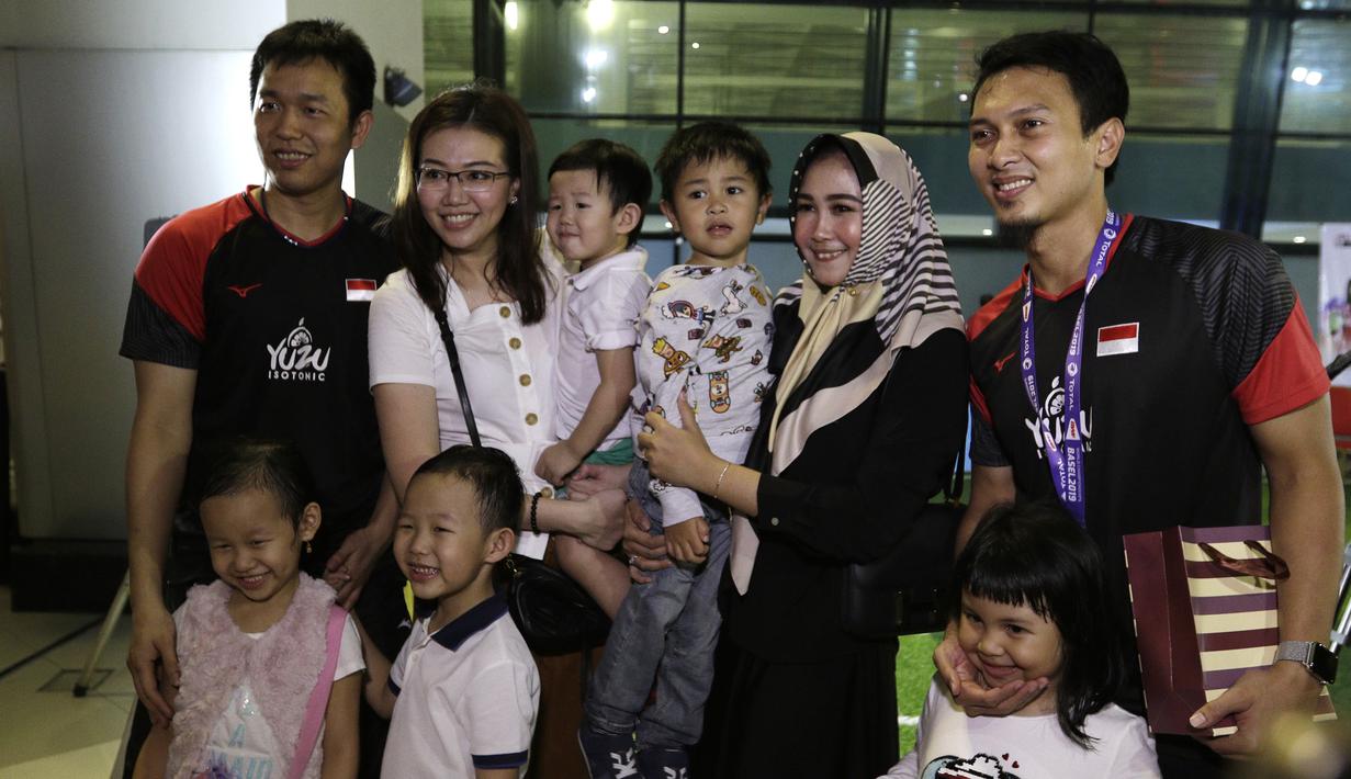Pasangan ganda putra Indonesia, Mohammad Ahsan/Hendra Setiawan, berfoto bersama keluarga usai konfrensi pers di Bandara Soekarno-Hatta, Tangerang, Selasa (27/8). Ahsan/Hendra meraih gelar pada Kejuaraan Dunia Bulutangkis 2019. (Bola.com/Yoppy Renato)