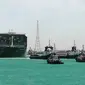 Kapal kargo Ever Given ditemani kapal tunda saat melaju di Terusan Suez, Mesir, Senin (29/3/2021). Ratusan kapal sedang menunggu untuk melewati kanal yang menghubungkan Mediterania ke Laut Merah. (Suez Canal Authority via AP)